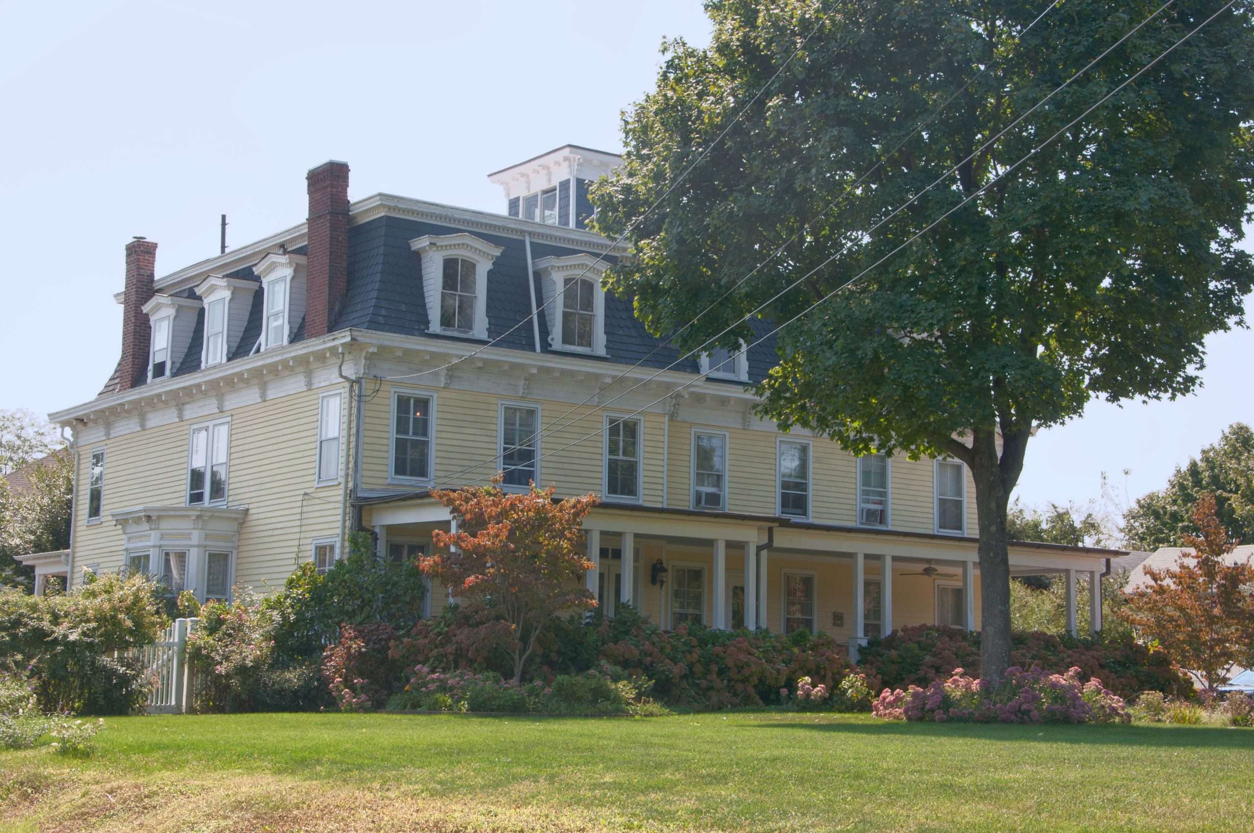 Large yellow historic house with garden and trees