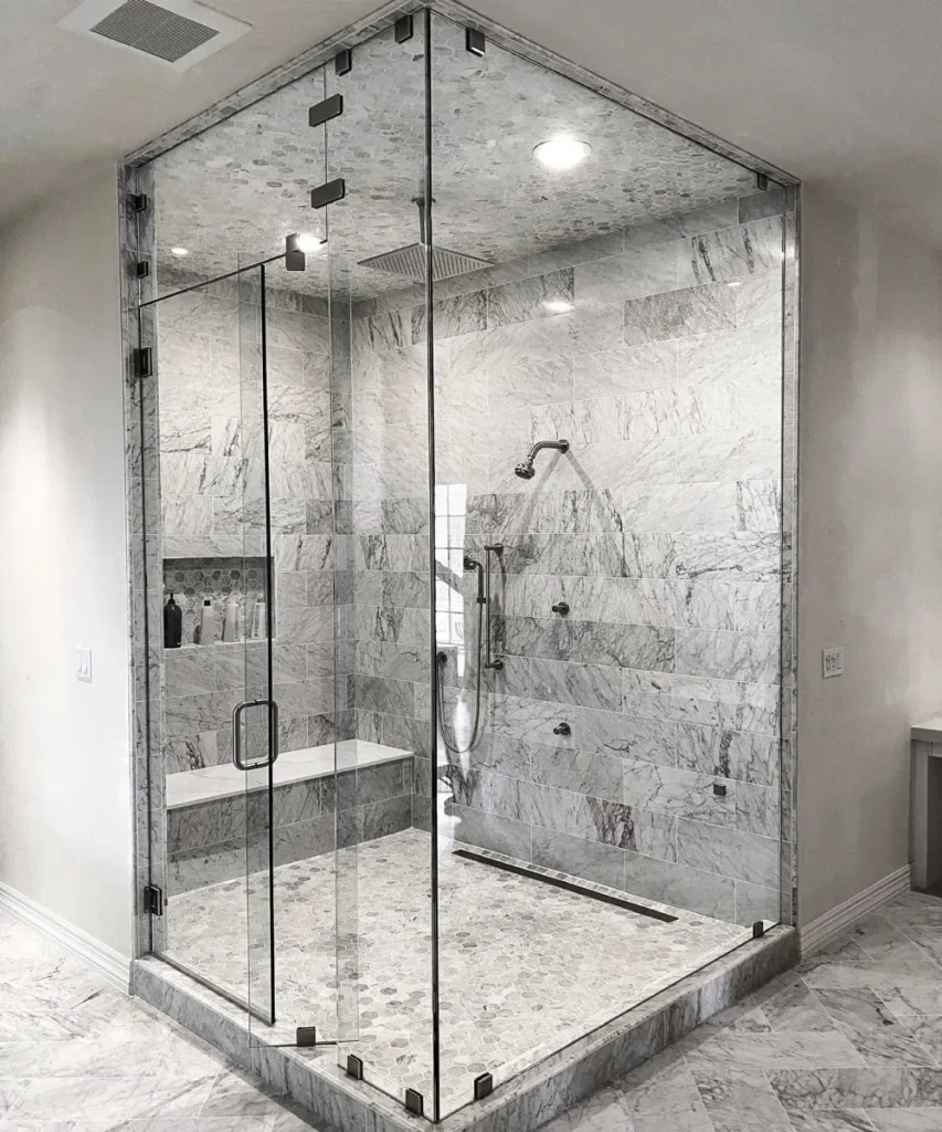 Luxurious marble corner shower with glass enclosure.