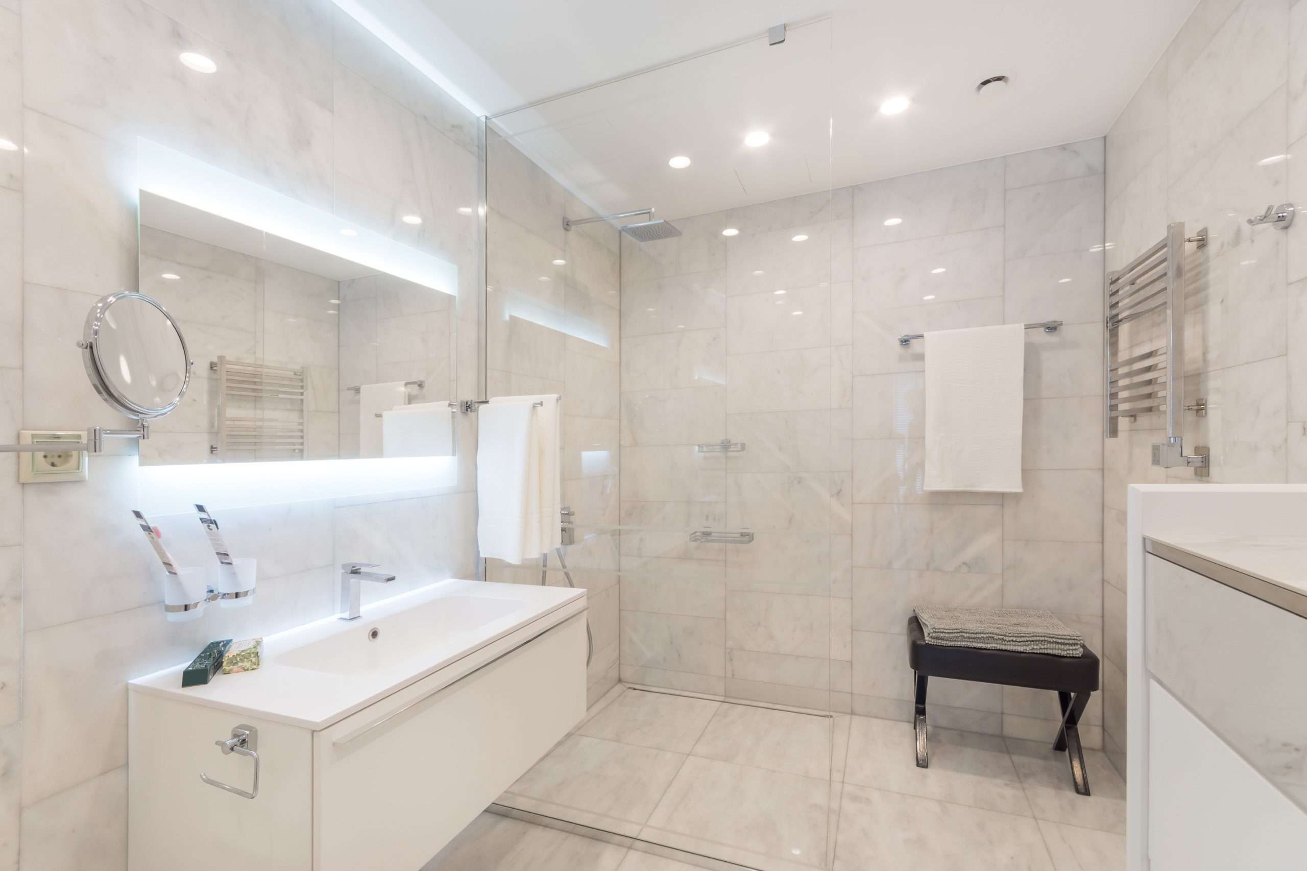 beautiful modern bathroom with large backlit illuminated mirror, sink, and glass shower